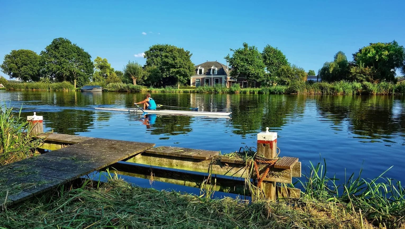 A woman in a rowboat rowing Amstelveen lake side