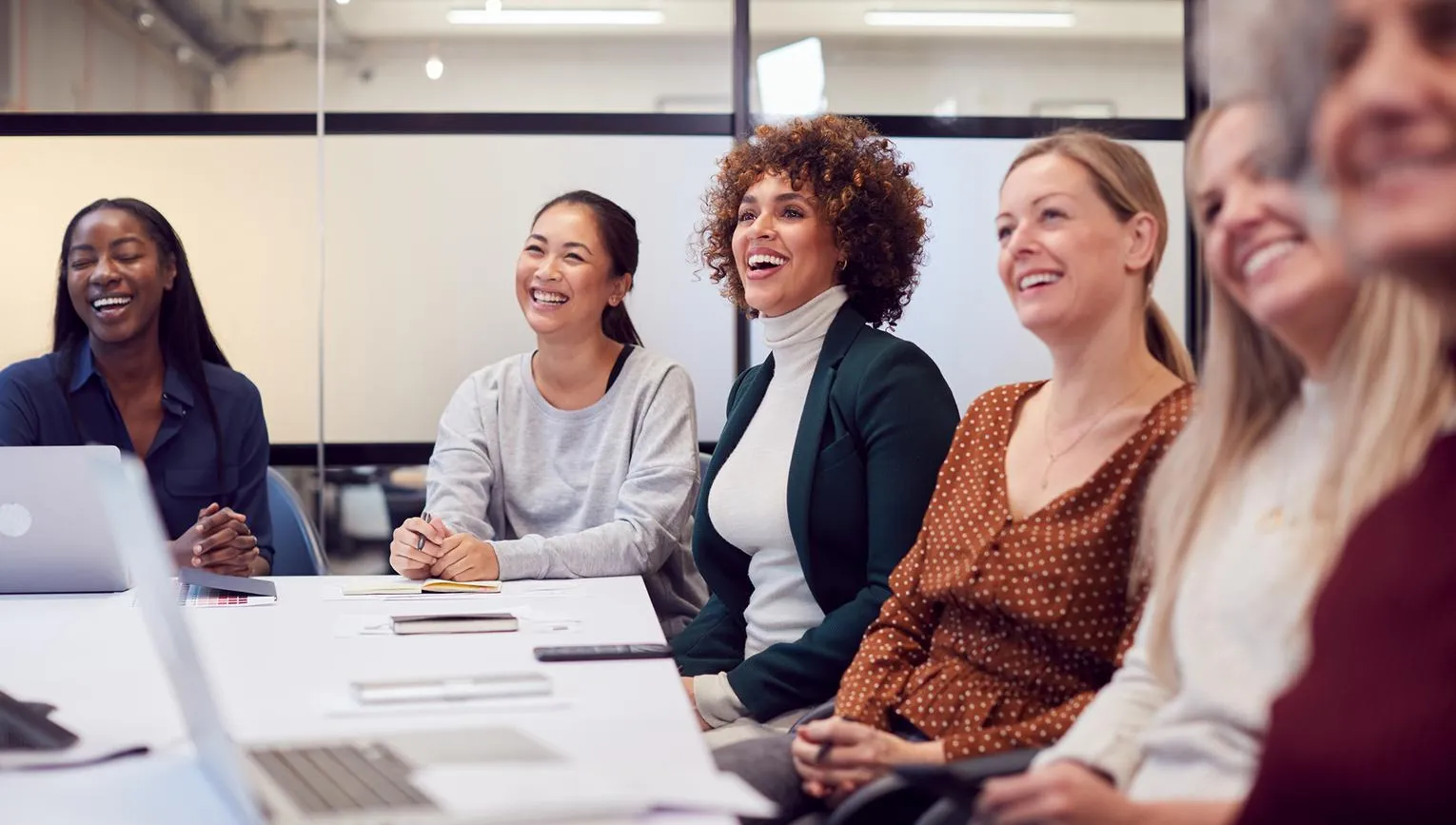 Line Of Businesswomen In Modern Office Listening To Presentation By Colleague