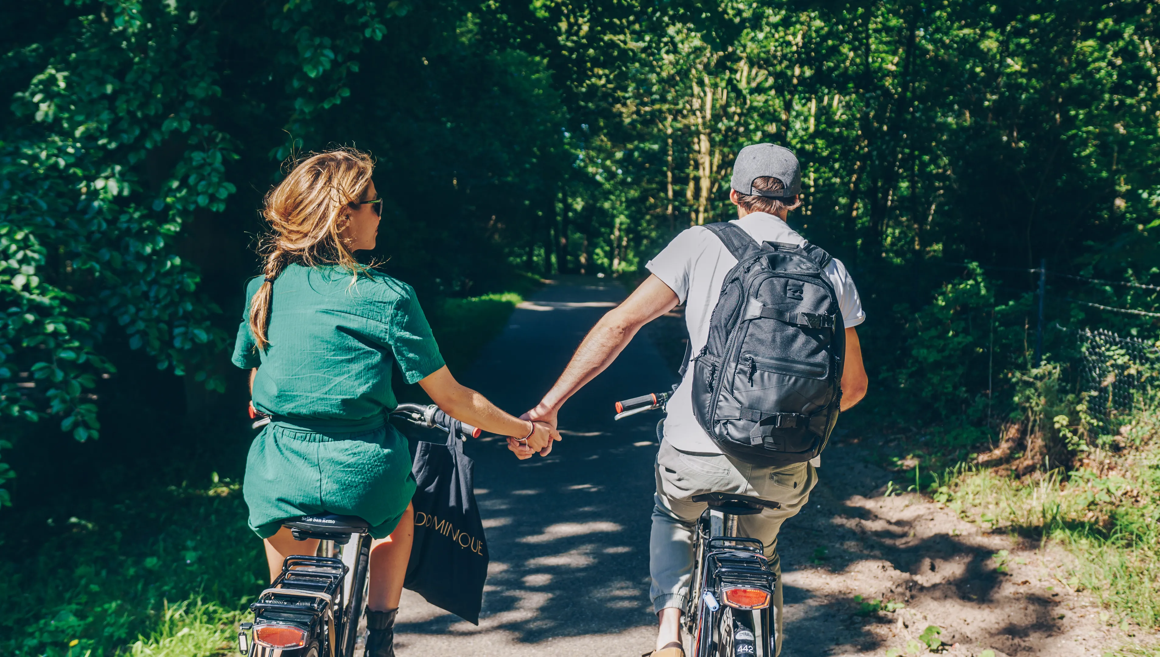 Couple cycling in the park holding hands