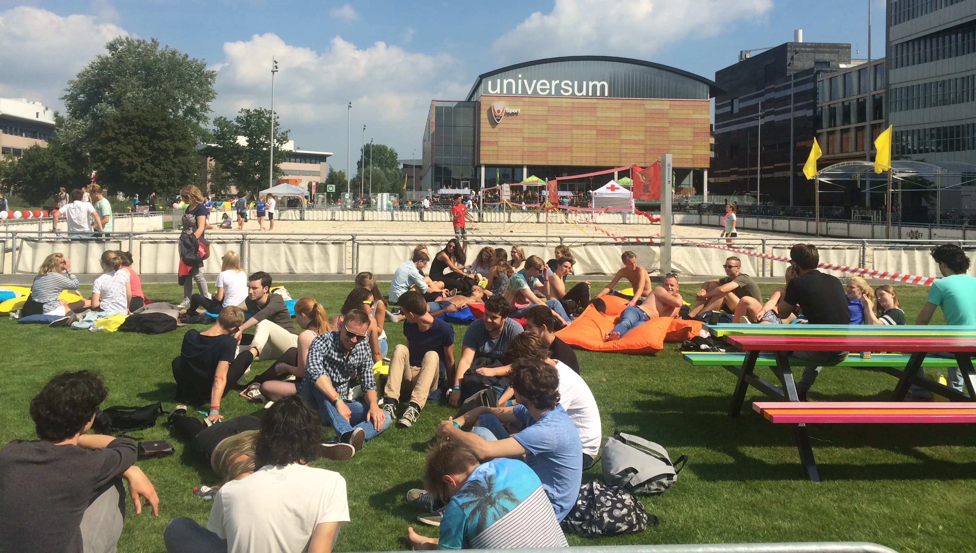 Students sitting on the grass in summer in front of University building of Physics UvA