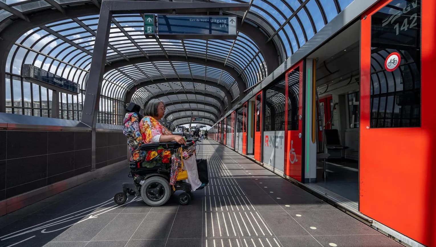 A person in an electric wheelchair enters the metro.