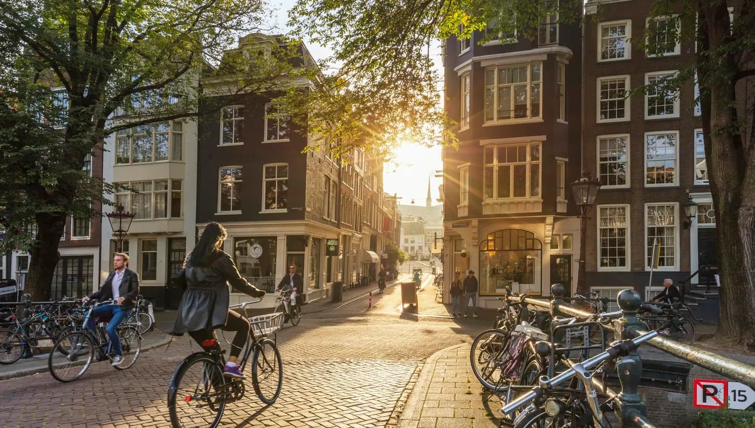 Amsterdam, Netherlands - September 22, 2021: Early morning in Amsterdam. Artistic image. People ride bicycles, the ancient European city of Amsterdam. Sunlight and silhouettes, beautiful downtown houses. Amsterdam, Holland, Netherlands, Europe