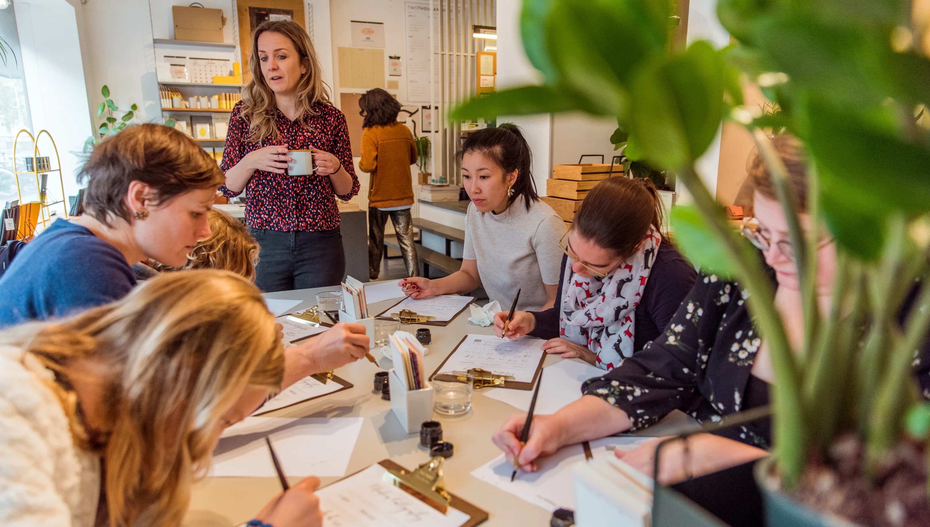People taking a Calligraphy workshop writing on a clipboard paper holder