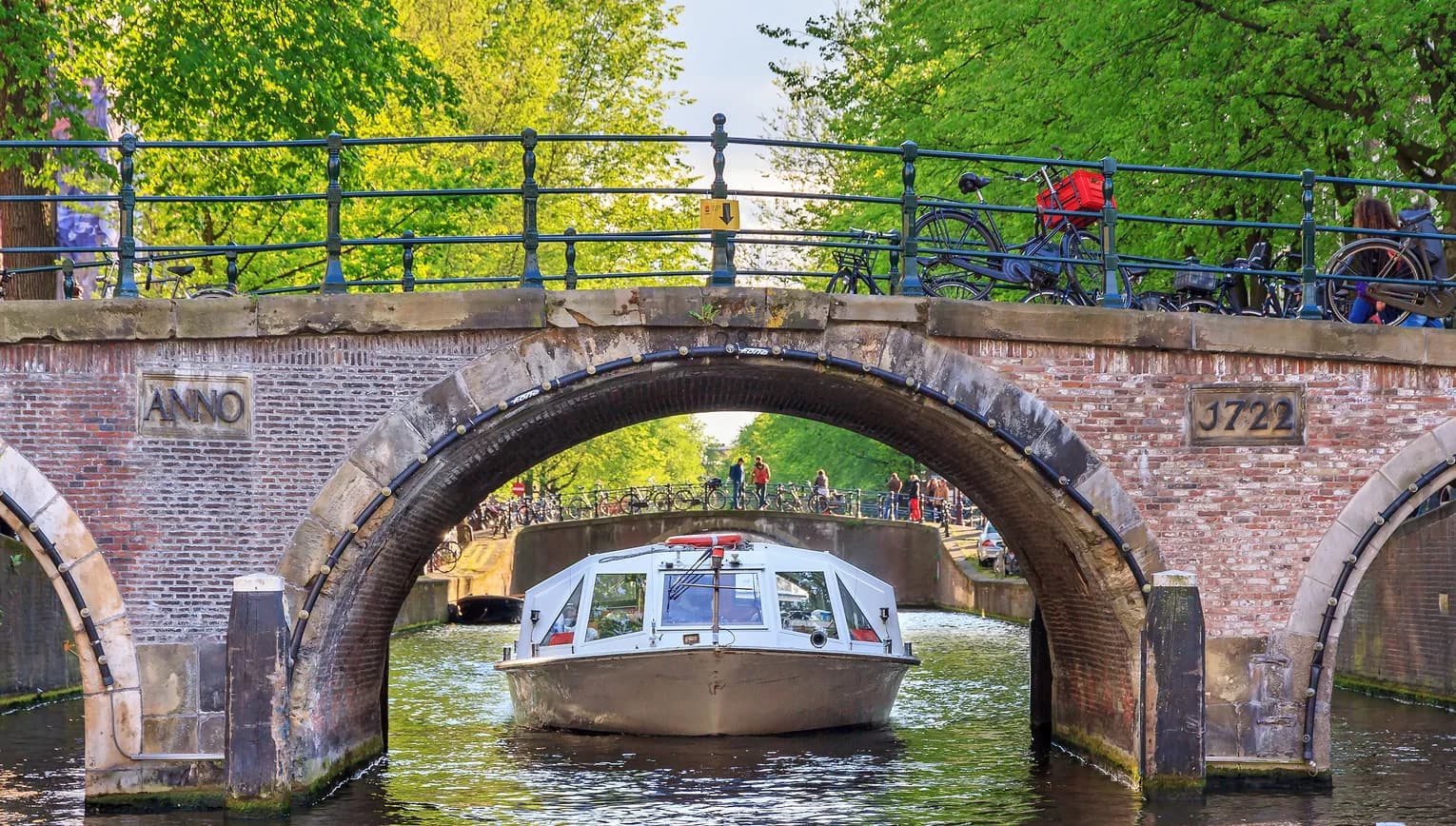 Canal cruise boat goes under the bridge over the Herengracht canal.