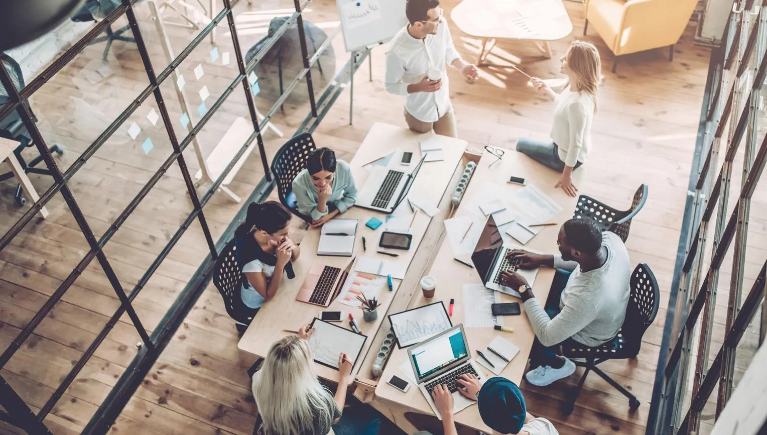 Top view of multiracial young creative people in modern office. Group of young business people are working together with laptop, tablet, smart phone, notebook. Successful hipster team in coworking. Freelancers.