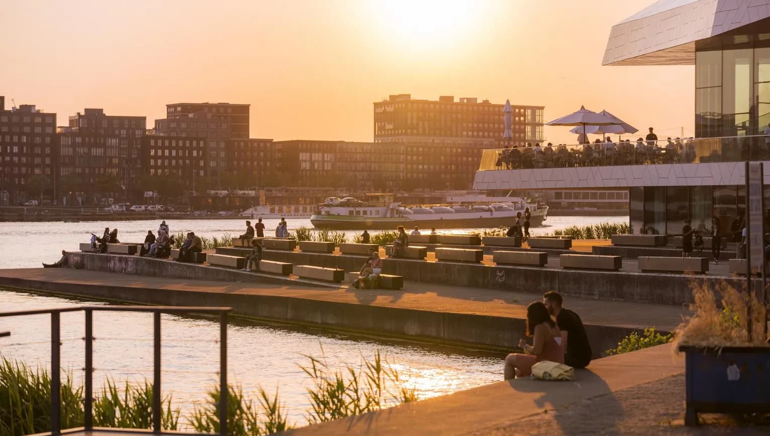 People enjoy the sunset at IJ-boulevard near EYE Filmmuseum.