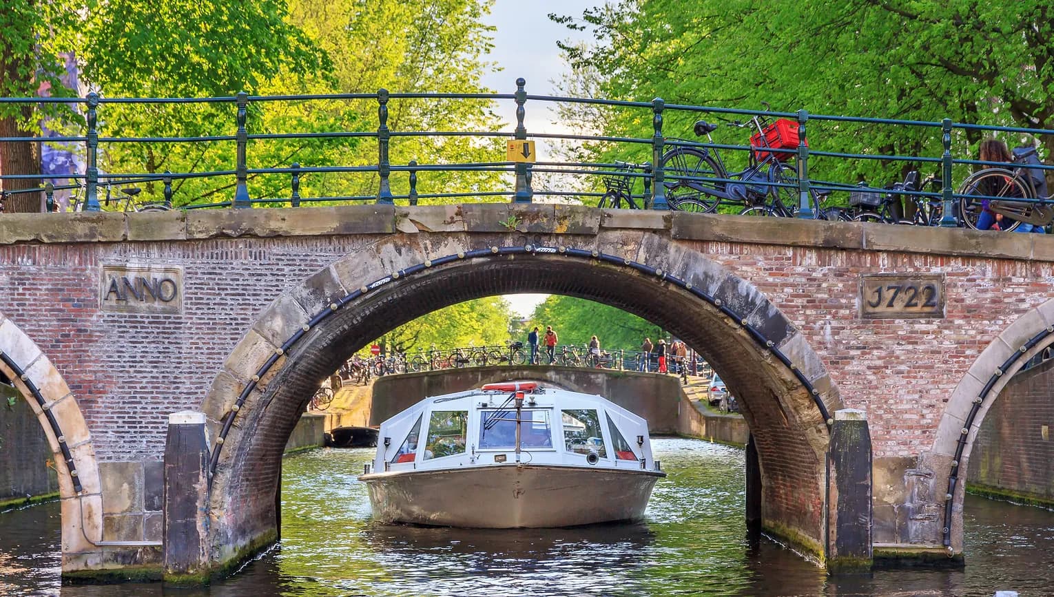 Canal cruise boat goes under the bridge over the Herengracht canal.
