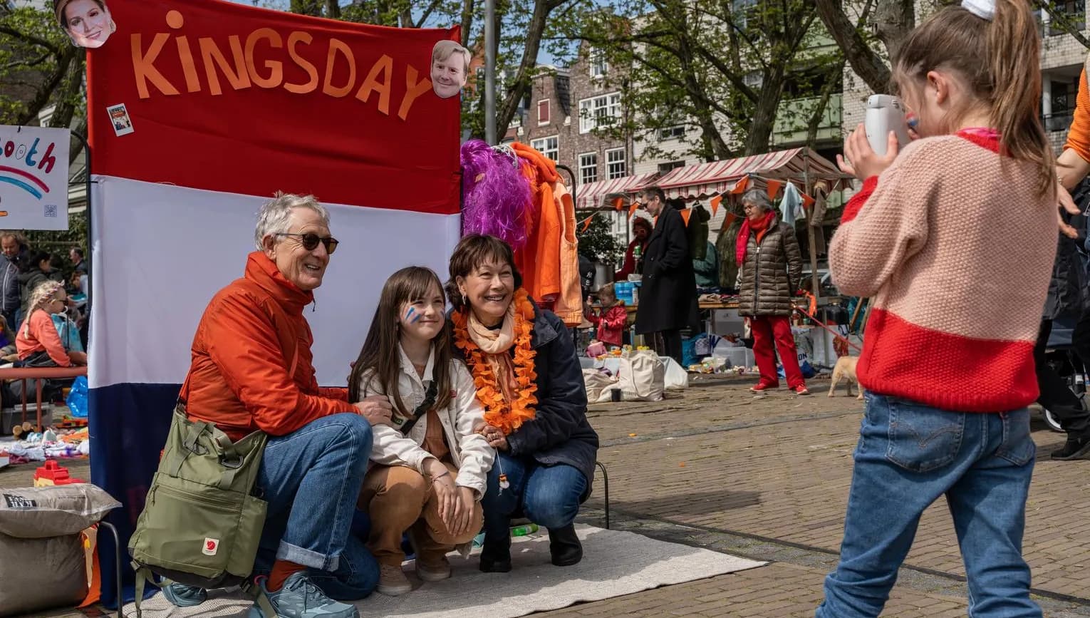 A family posing for a picture on the Amstelveld flea market on King's Day 2023.