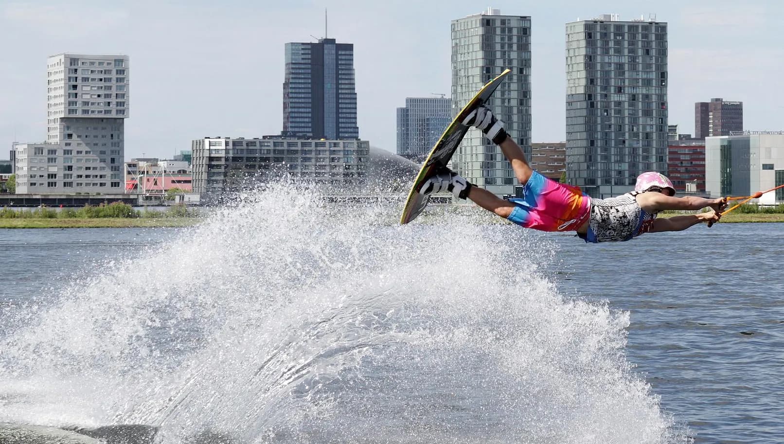 Wakeboarder doing jump at Cablepark Almere with city skyline