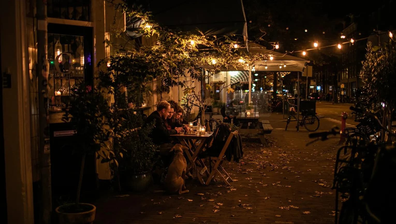 People sitting on terrace at night at Compartir wine bar and restaurant on Spaarndammerstraat