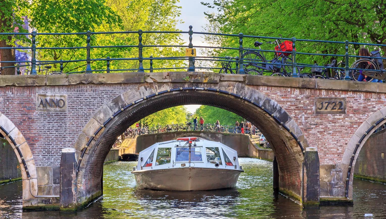 Canal cruise boat goes under the bridge over the Herengracht canal.