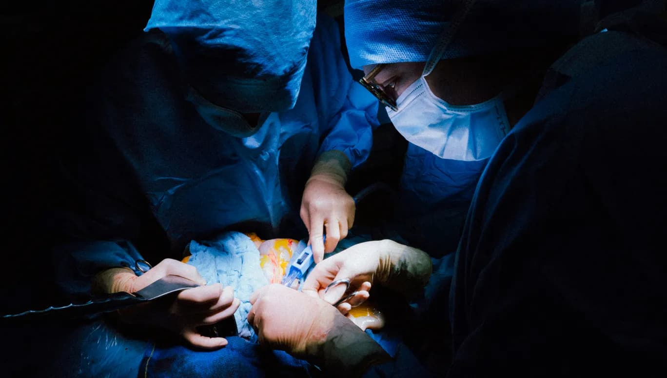 Closeup of two doctors performing heart surgery in operating room.