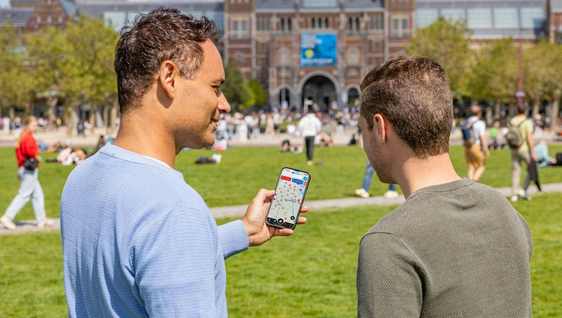 Two men on Museumplein check the Digital City Card app together.