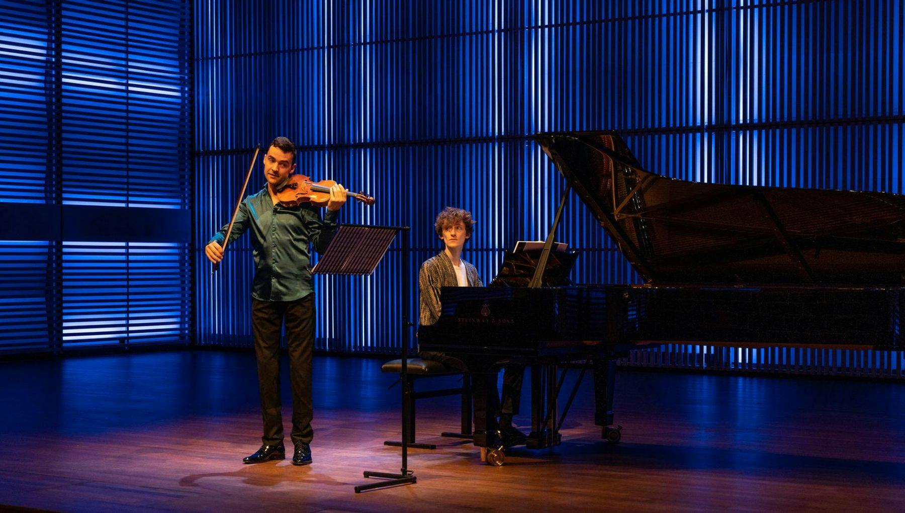 A violinist and a pianist on stage in het Muziekgebouw aan 't IJ