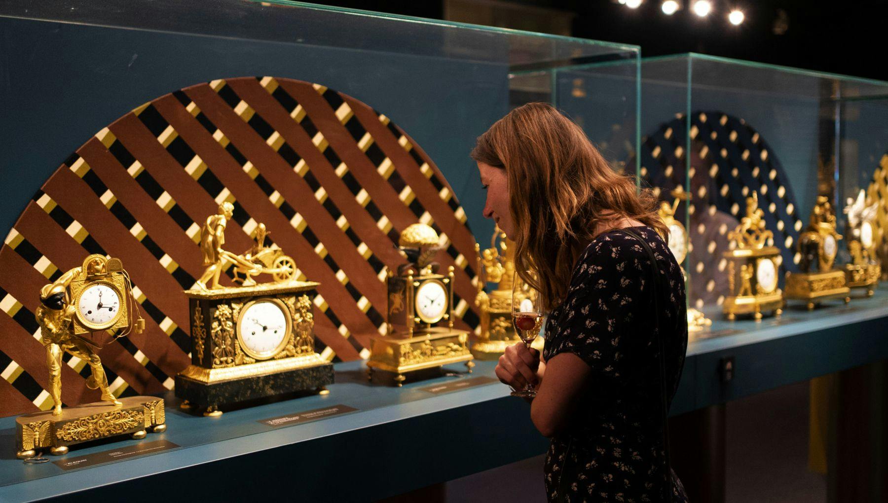 A woman looking at one of the pendulums in the exhibition 'Once Upon A Time' with eighty fire-gilded bronze mantel clocks that can be seen in the new pop-up museum on Museumplein.