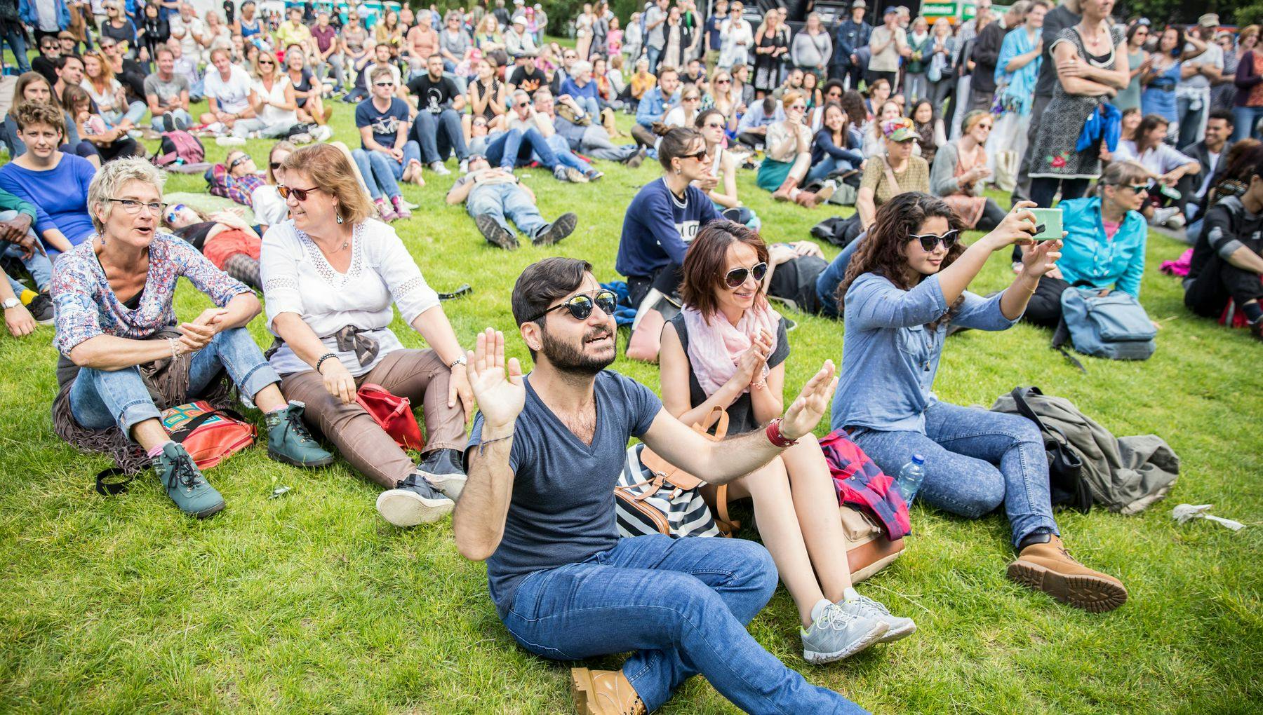 Amsterdam, The Netherlands - July, 3 2016: visitors sitting on the grass and cheering during Roots Open Air festival