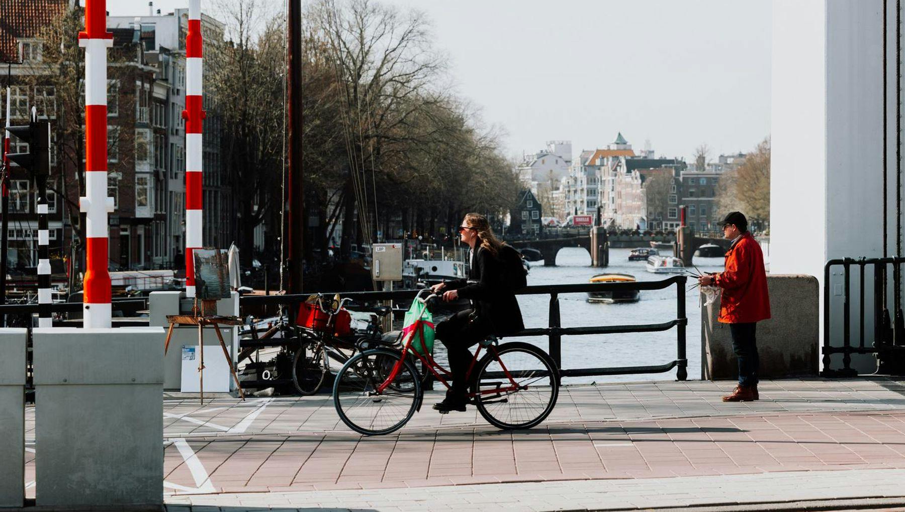 A woman biking past a painter on the bridge