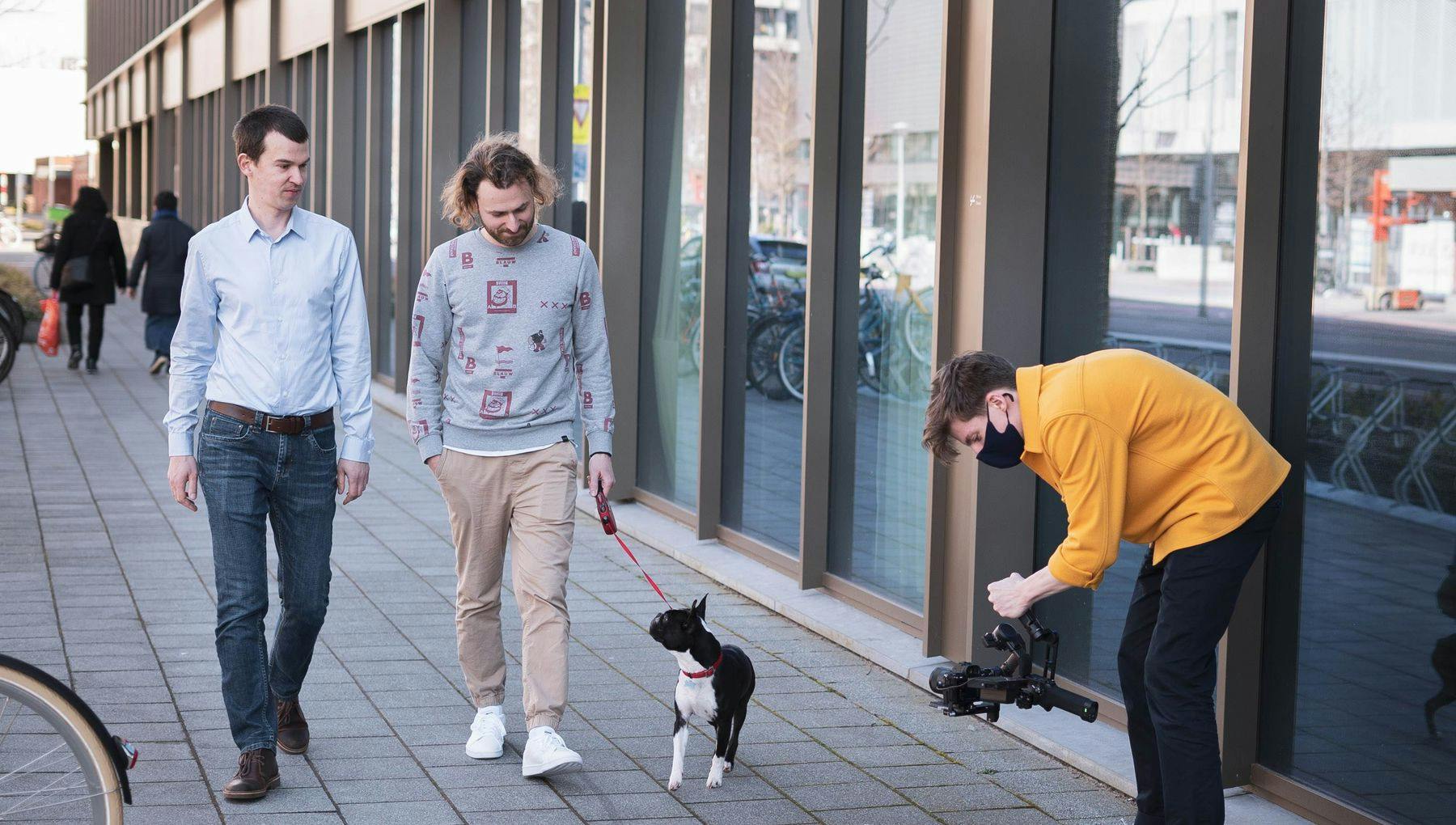 Cooper Pet Care co-founders Pavel Timofeev and Michael Fisher walking a dog in the street, with someone filming them.