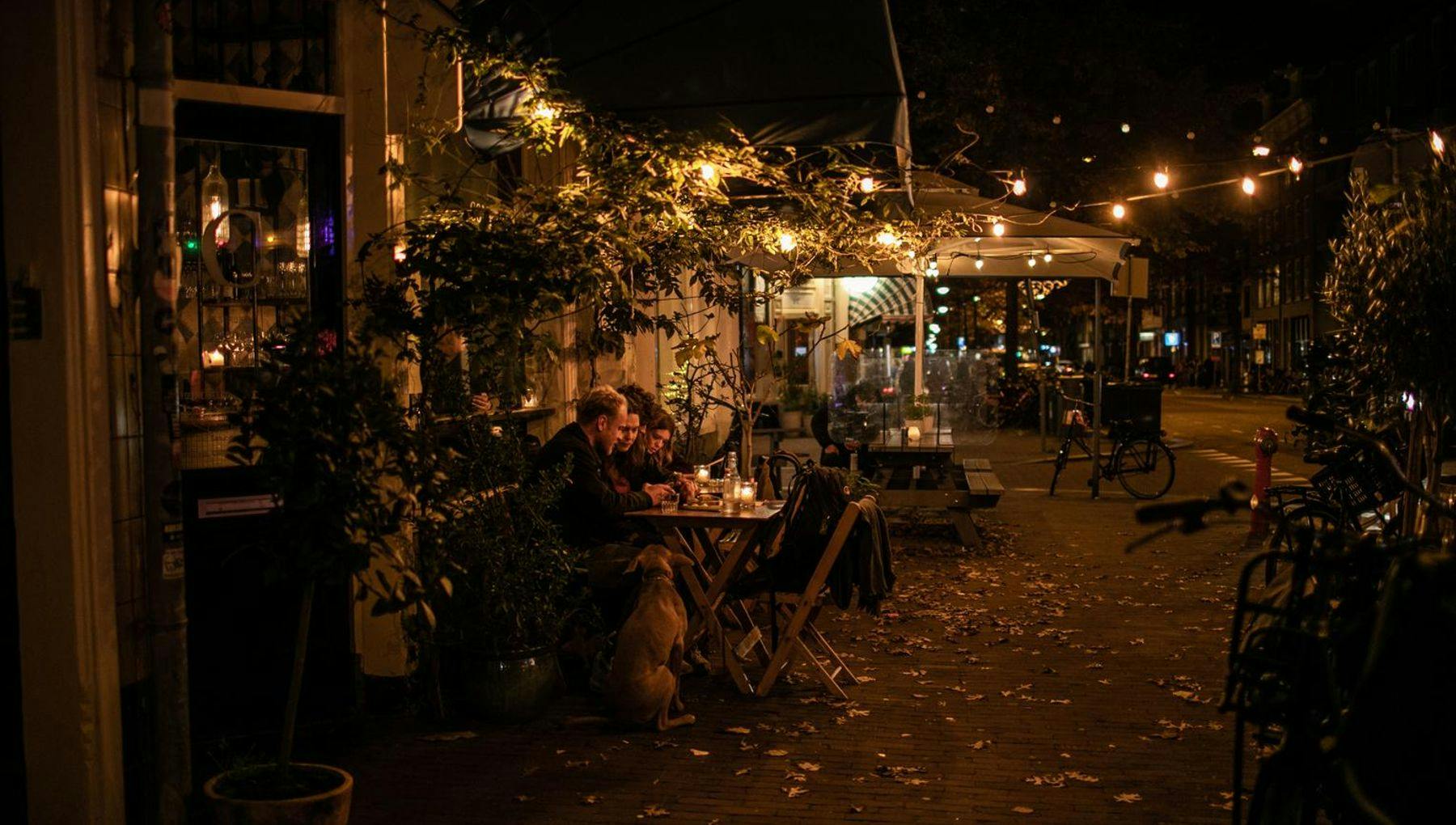 People sitting on terrace at night at Compartir wine bar and restaurant on Spaarndammerstraat