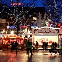 Festive market stalls on Rembrandtplein, surrounded by trees festooned in Christmas lights.