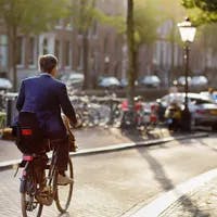 An elegantly dressed man rides a Bicycle in the center of Amsterdam. Bicycle capital of Europe.