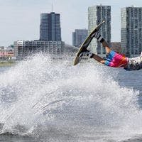 Wakeboarder doing jump at Cablepark Almere with city skyline