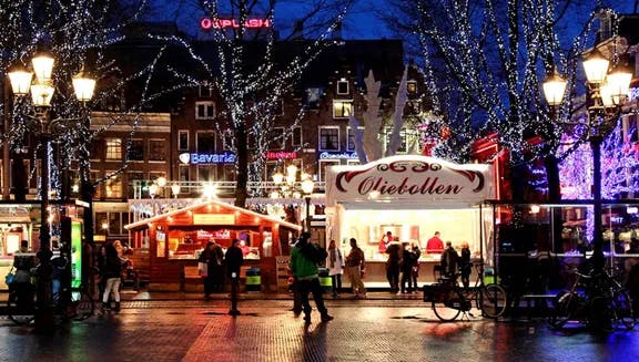 Festive market stalls on Rembrandtplein, surrounded by trees festooned in Christmas lights.