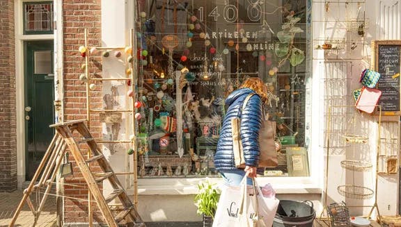 Woman with shopping bags looking in the window of Sjakies gift and concept store on shopping street. Haarlem Content Creation Day March 2024