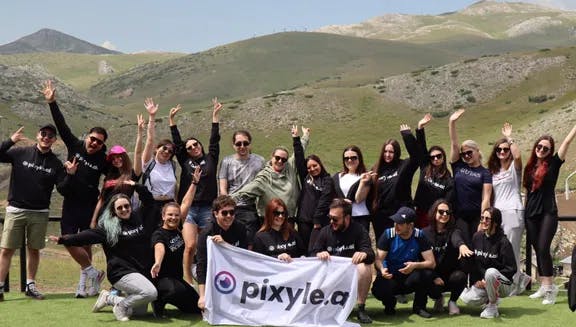 Pixyle.ai team outside in hilly landscape holding banner