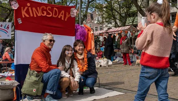 A family posing for a picture on the Amstelveld flea market on King's Day 2023.
