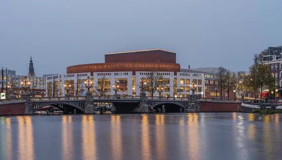 The National Opera & Ballet at nightfall, seen from a distance. This cultural institution is located at the Amstel river, close to Waterlooplein in the city centre.