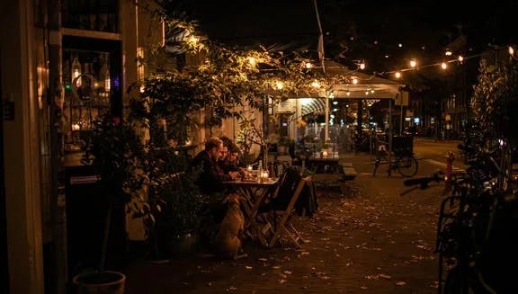 People sitting on terrace at night at Compartir wine bar and restaurant on Spaarndammerstraat