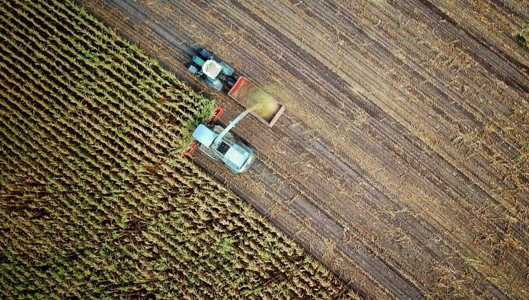 Aerial shot of two tractors harvesting crop