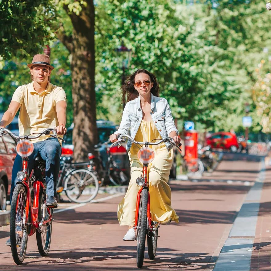 Young happy couple on red bikes cycling on the old streets in the city centre.