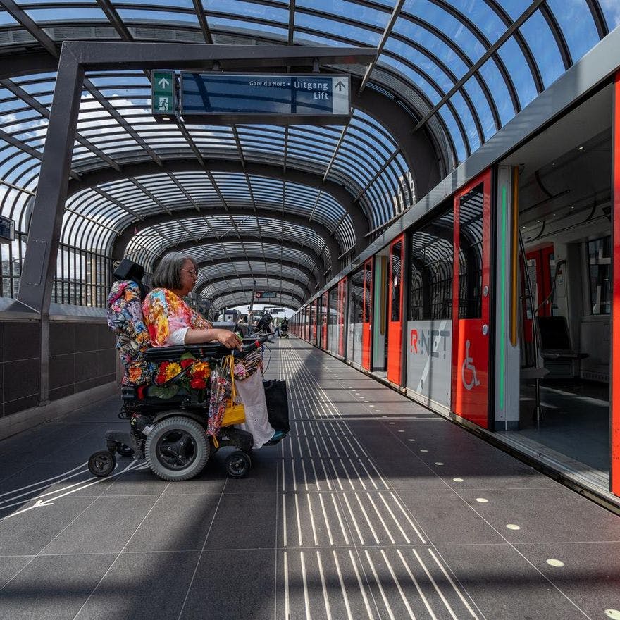 A person in an electric wheelchair enters the metro.