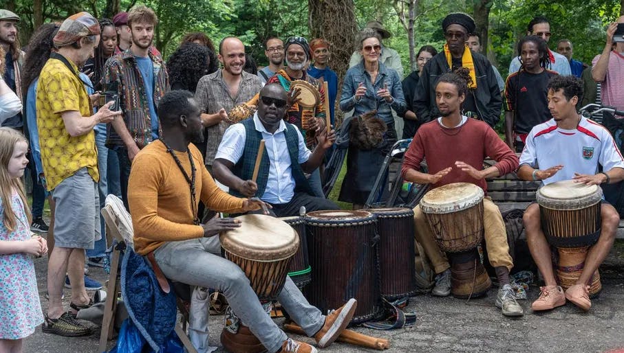 Musicians playing djembe while spectators watching and listening during Keti Koti Festival 2022 in the Oosterpark.