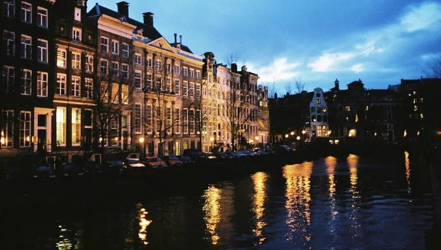 Amsterdam canal at night with reflections of lights on water