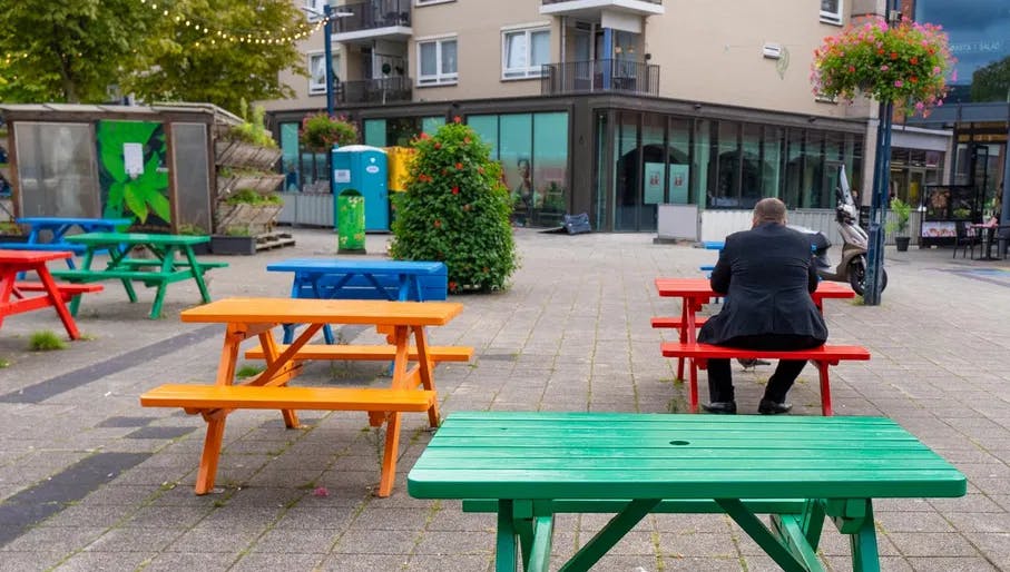 Westmarket shopping mall at Osdorpplein in Nieuw-West, food court and shops. Man sitting outside having lunch at colorful picnic tables