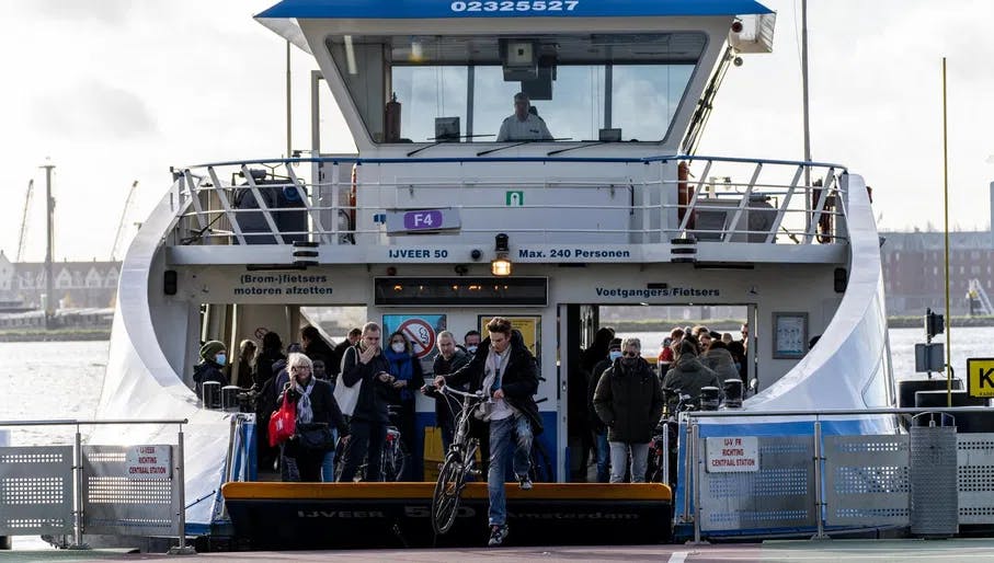 A busy ferry is about to depart. A person quickly jumps off it with his bicycle before the valve closes.