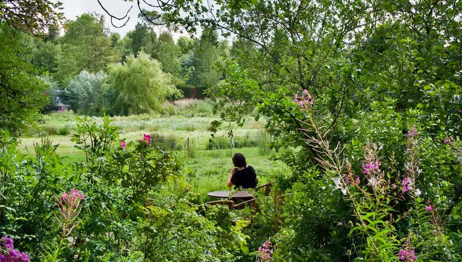 A person sits in the garden of the Buurtboerderij