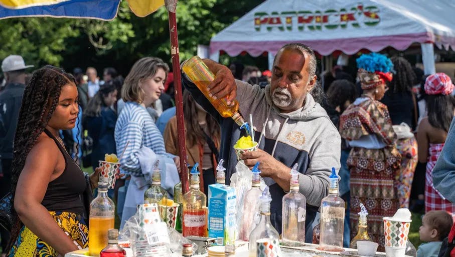 A man preparing so called 'schaafijs' (shaved popsicle) during Keti Koti Festival 2022 in the Oosterpark.