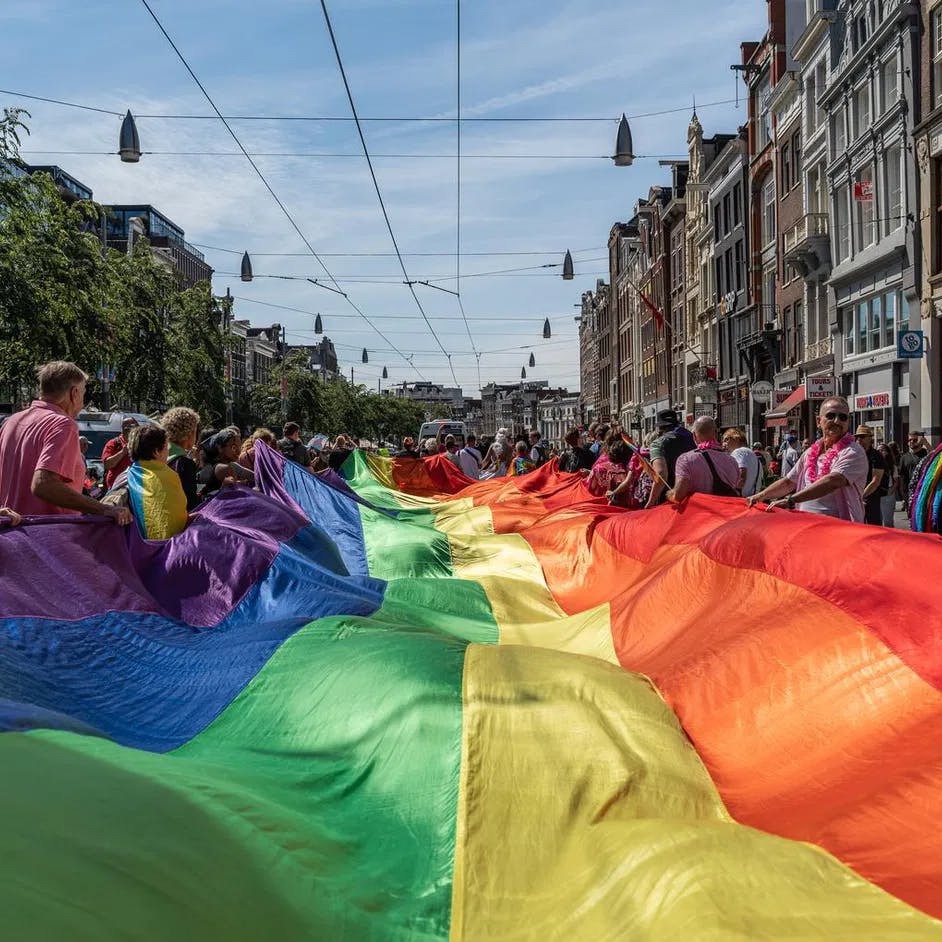 A crowd of people marching with a pride flag.