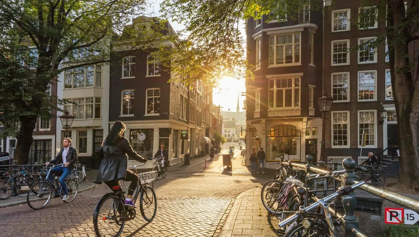 Amsterdam, Netherlands - September 22, 2021: Early morning in Amsterdam. Artistic image.  People ride bicycles, the ancient European city of Amsterdam. Sunlight and silhouettes, beautiful downtown houses.  Amsterdam, Holland, Netherlands, Europe